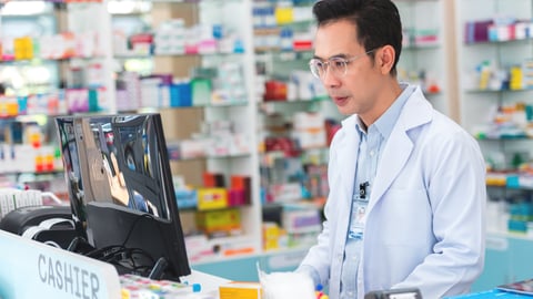 Middle-aged east Asian pharmacist looking at his computer