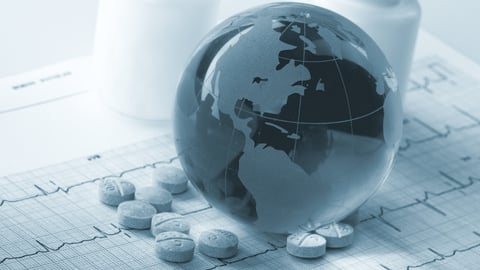 A glass globe sits among medicine bottles and pills