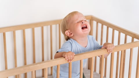 Blonde toddler crying in his crib