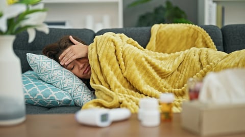 Young woman sick on the couch under a yellow blanket