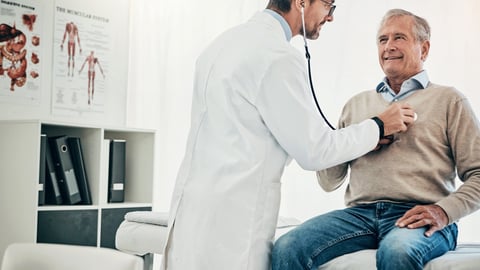 A physician listening to the heartbeat of an older male patient