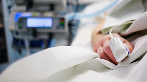 Finger of patient with a heart monitor in a hospital bed