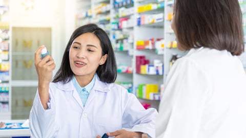 Pharmacist holding up an inhaler to show other person
