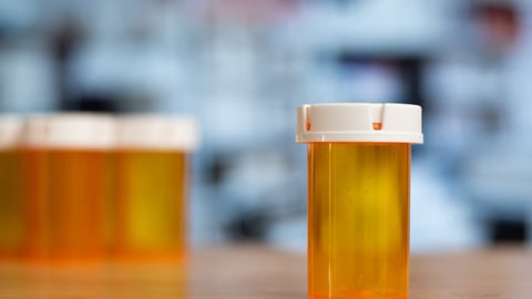 An empty bottle of medicine with many empty bottles in background.