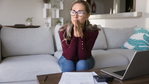 Older woman thinking about the pile of paperwork she has in front of her
