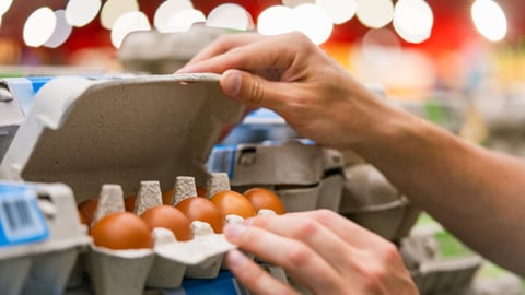 A person opens a carton of eggs.