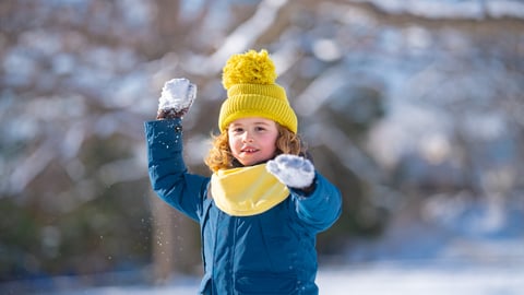 Little girl playing in the snow getting ready to throw a snowball