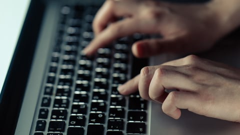 Hands typing on a laptop