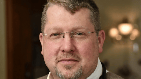 Dr. Darren Cargill, a fair-skinned male doctor with glasses