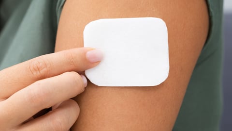 A young woman applying a medication in patch form