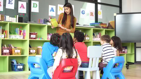 A young woman teacher reading to a class of kindergarteners 