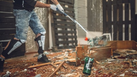 Man smashing a bottle with a gold club in a rage room