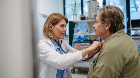 Woman doctor listening to the heartbeat of an older woman patient