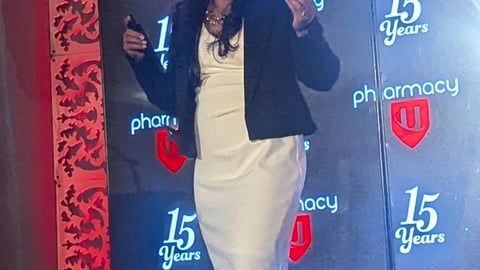 Dark skinned woman in white dress with black jacket on a stage