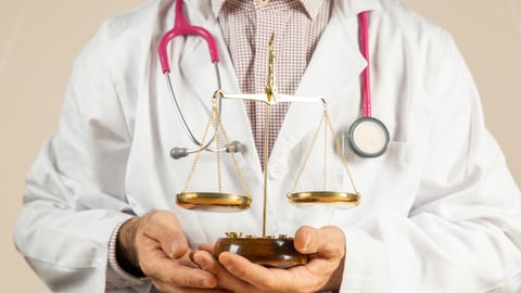 A close-up of a doctor wearing a stethoscope while carrying a legal scale.