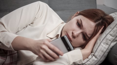 A girl lying on a couch with a phone in her hands.