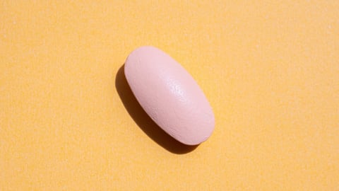 Pink medicine pill tablet on orange background