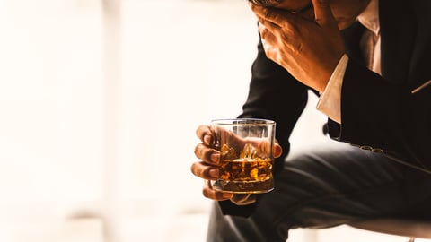 A man in a suit holding an alcoholic drink.