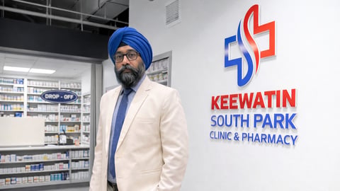 Amarjeet Makkar standing in front of the logo of his business