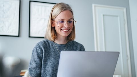 Smiling woman using a laptop indoors.