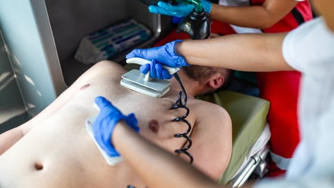 A healthcare worker uses a defibrillator on a patient.
