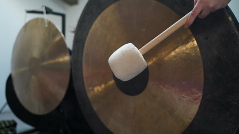 A person hits a gong with a mallet.