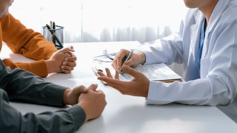 A couple attends a meeting with a physician at a fertility clinic.