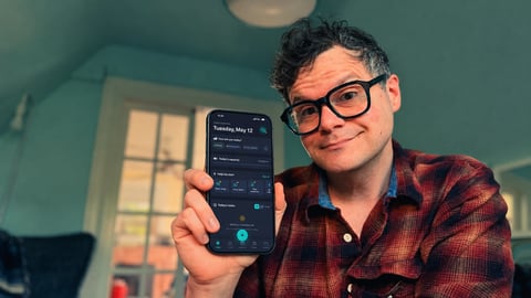 James Smith holding up his phone to show off his app