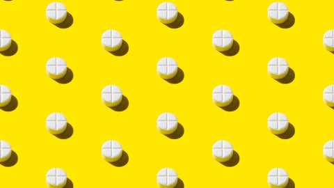 A spread of white pills on a yellow background