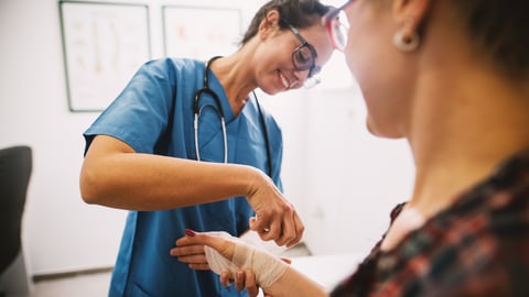 Nurse wrapping a patient's wrist and hand in gauze