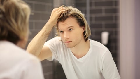 A young white man looking in the mirror