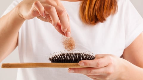 A woman with red hair with pulls out hair from a hair-comb. 