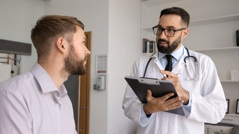 A male doctor sees a patient in his office.