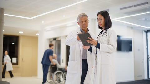 Two doctors chatting, reading notes on a tablet