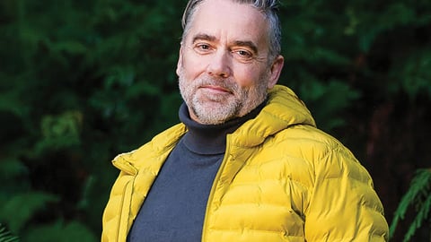 Dr. Adam Thompson in a bright yellow jacket in the woods