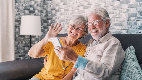 An older white couple video chatting with someone on a smartphone