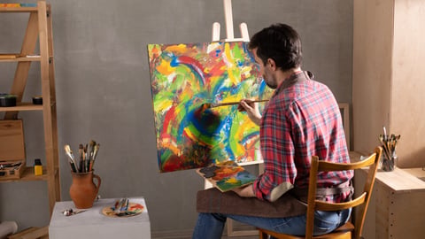 An artist paints a painting on an easel.