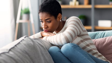 Portrait of an upset woman setting on a couch.