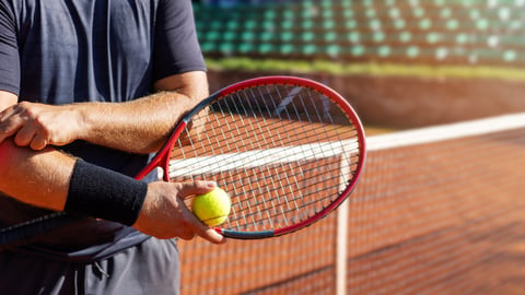 Male tennis player torso, holding racket and holding elbow as if sore