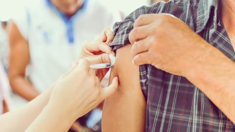 A person rolling up their sleeve and getting a shot