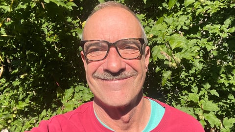 Colin Leslie, man with red sweatshirt and leaves behind