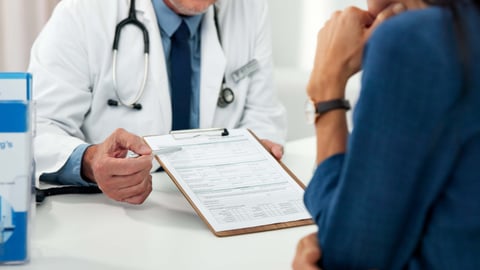 A doctor shows a patient paperwork.
