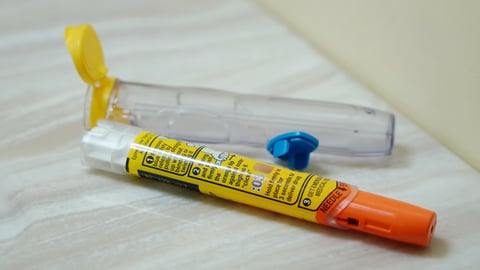 Used Epipen auto injector lying discarded by the side of the sink.
