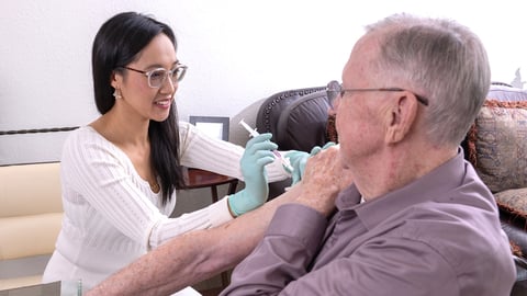 Pharmacist Yolanda Yeung giving a vaccine to a patient in his home