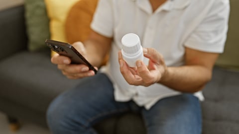 A patient holding a pill bottle and a cell phone.