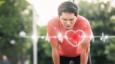 Man in red shirt bent over as if tired from exercise, with heart and heartbeat graph overlaid