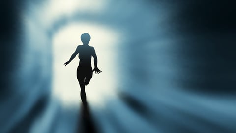 A shadowy figure running towards the light coming through an open door