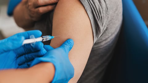Close up of an arm with a rolled up sleeve about to get a vaccine