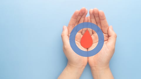 A pair of hands holding a symbol for a drop of blood