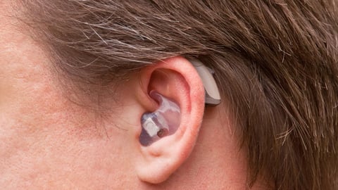 Close-up of a man ear with a high-tech digital behind-the-ear-hearing device; Shutterstock ID 104835074